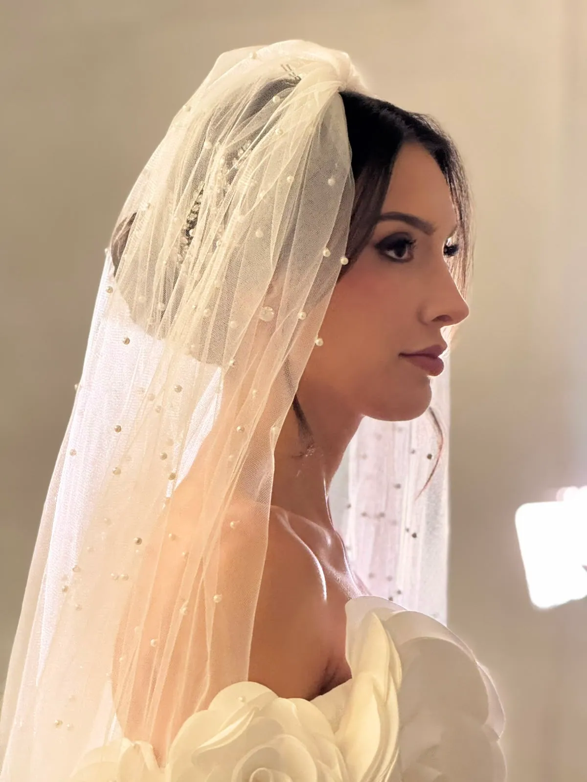 Retrato de noiva de perfil com véu de pérolas e vestido de rosas